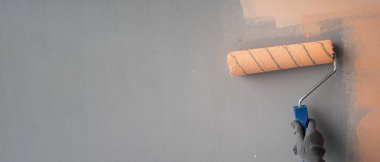 Dekoratörün duvarları silindirle boyadığı yakın plan. Boşluğu kopyala