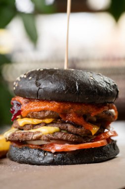 Köfteli ve pastırmalı, peynirli ve sebzeli hamburgerin yakın çekimi, ahşap masanın üzerinde. opi alanı