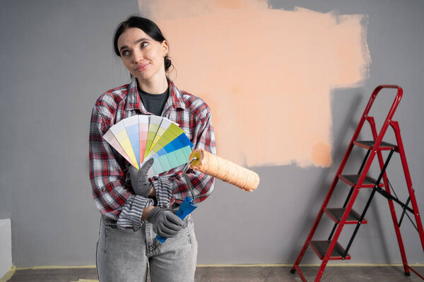 Female interior designer with palette samples on color background. Choosing colors for painting walls