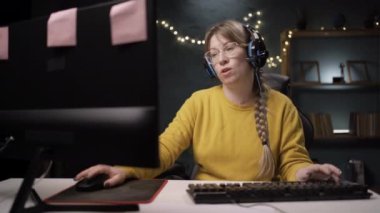 Oyuncu, çevrimiçi video oyununda mikrofondaki ekiple konuşuyor. Kulaklıklı kadın diğer oyuncularla oynar ve el sallayıp gider. Boşluğu kopyala