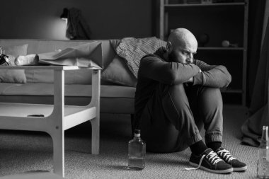 Düşünceli bir adam elinde bir şişe alkolle evde oturuyor. Depresyonla mücadele. Boşluğu kopyala