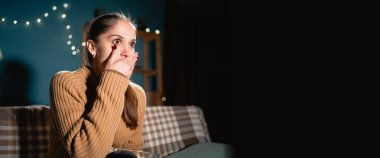 Gecenin geç saatlerinde şok olmuş ve korkmuş bir kadın, patlamış mısır yiyor ve televizyonda korku filmi seyrediyor. Pankart. Boşluğu kopyala