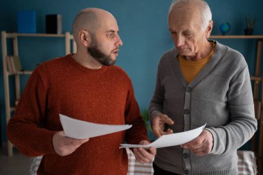 Yaşlı baba, yetişkin oğluyla oturma odasında oturup iki adamın hafta sonu evde ödemeleri ve mali belgeleri tartışmasını tartışıyor. Boşluğu kopyala