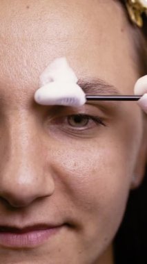 Modellerin kaşlarına nemlendirici köpük sürme ustası. Yakın plan. Dikey video