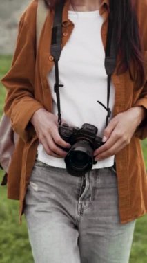 Sırt çantalı bir kadın gezgin ve elinde bir dslr kamerayla baharda dışarı çıkıyor. Boşluğu kopyala