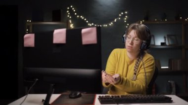Oyuncu, mikrofonla çevrimiçi video oyununda takımla konuşuyor. Kulaklıklı bir kadın diğer oyuncularla oynuyor ve canlı yayında yardım isteyen bir dilencinin hareketlerini gösteriyor.