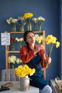Dişi bir çiçekçi çiçekçi dükkanında çalışırken güzel bir bahar çiçeği buketi toplar. Boşluğu kopyala