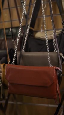 Bir aksesuar dükkanının vitrininde farklı renklerde deri çantalar asılı. Boşluğu kopyala