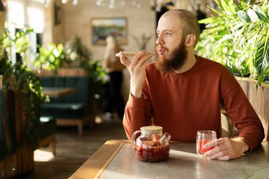 Samimi bir kafede sakallı bir adam akıllı telefonuna sesli mesaj yazdırıyor. Elinde yeşilliklerle çevrili bir bardak bitki çayı tutarak uzayın rahatlatıcı atmosferinin tadını çıkarıyor..