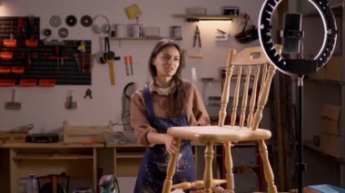 İspanyol kadın DIY blogger cep telefonu ve ahşap işçiliği hobisinin halka lambasıyla video kaydediyor. Boşluğu kopyala