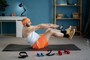 Fitness ve kişisel bakım konsepti. Parlak spor giyimli bir adam, evde teknede poz veriyor, denge ve çekirdek kuvvete azimle odaklanıyor ve kişisel egzersiz rutinine odaklanıyor.