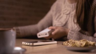 Akşam kafede otururken elektrik bankasıyla şarj olan kadın kıyafetleri. Boşluğu kopyala