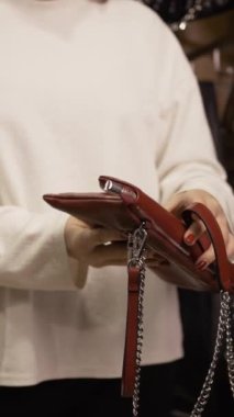 Kadın el çantası seçiyor. Omuz çantaları kadınlar için. Kahverengi çanta, yakın plan. Dikey video