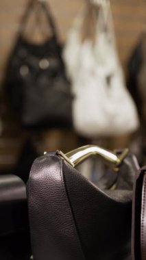Moda mağazasında deri çanta ve aksesuar seçen genç bir kadın. Dikey Görüntü