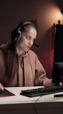 Kulaklık takan oyuncu evde video oyunu oynuyor. Esportçu, bilgisayar oyunları turnuvasında el hareketleriyle bana el hareketi yaptı. Dikey video