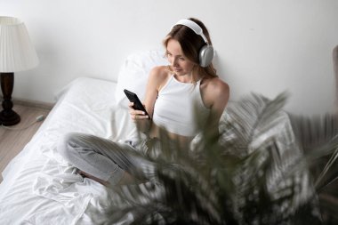 Yatak odasında rahat bir şekilde müzik dinleyen rahat sarışın kız. Boşluğu kopyala