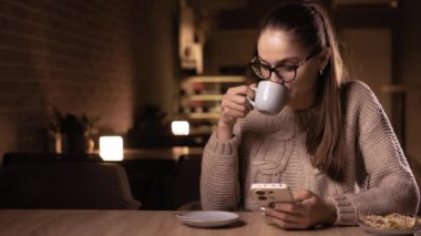 Kahve içip cep telefonu kullanan yorgun iş kadını gece geç saatlerde kafede çalışıyor. Boşluğu kopyala