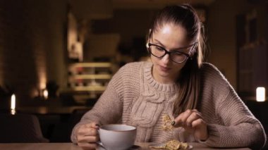 Gözlüklü, fındıklı elma yiyen ve kafeinsiz kahve içen rahat bir kadın. Boşluğu kopyala