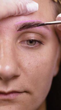 Güzellik uzmanının kadın kaşlarına kına boyası uygulaması, şekillendirme ve geliştirme, profesyonel kaş boyama prosedürü, güzellik ve kendine bakım. Dikey video