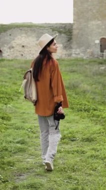 İlkbaharda tarihi kalede yürüyen turist fotoğrafçısı sırt çantası ve kamera taşıyor, mimari ve simgeleri, seyahat, macera, gezi, gezi ve tarih kavramlarını yakalıyor.