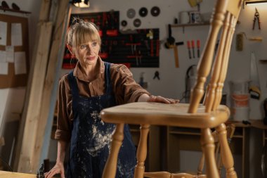 Küçük işletme konsepti. Orta yaşlı bir kadın atölyesindeki eski mobilyaları restore eder ve onarır. Boşluğu kopyala