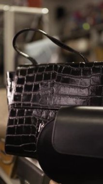 Moda mağazasındaki bir raftan lüks bir çanta seçen bir kadının yakın çekimi. Dikey video