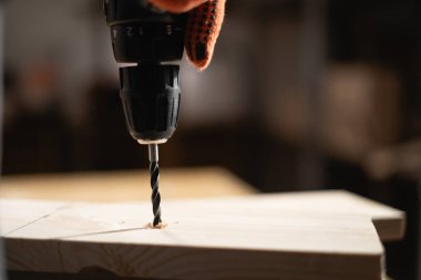 Marangoz elektrikli matkap kullanıyor. Katılımcı masaya tahta deliyor. Doğrama işi ve küçük işletme konsepti