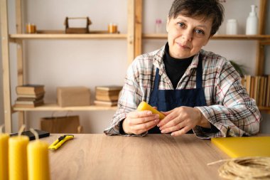 El yapımı mum konsepti. Balmumu vakfından mum yapan orta yaşlı kadın ev ofisinde çalışıyor, küçük işletme ve yeni bir konsept başlatıyor.
