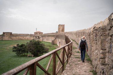 Yaşlı turist Avrupa 'daki ortaçağ kalesini ziyaret ederek tuğla duvar boyunca yürüyor. Boşluğu kopyala