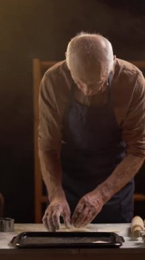 Yaşlı bir fırıncı kalp şeklinde kurabiyeleri fırına koyar, onları fırına hazırlar, geleneksel pişirme konsepti ve Sevgililer Günü kutlamaları için..