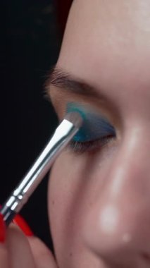 Güzellik konsepti Makyöz, kadın model yüzü için göz farı takıyor. Yakın plan. Dikey video