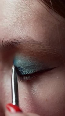 Makyaj konsepti. Makyöz kadın yüzüne fırçayla göz farı sürüyor. Göz farı. Boşluğu kopyala