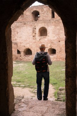 Kıdemli turist tuğla duvarların kemerlerinde sonbahar tatilinde yürüyen antik kalede. Turizm ve seyahat kavramı