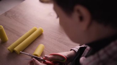 Fitil kesen bir kadın atölyede otururken kokulu mum yapıyor. Boşluğu kopyala