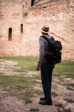 Şapkalı kıdemli turist Antik Akkerman Kalesi 'ne tek başına gezmeye gidiyor. Boşluğu kopyala