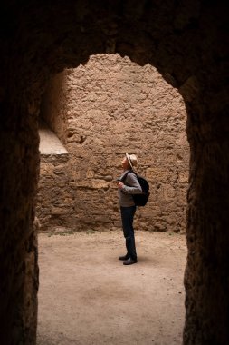 Kıdemli turist tuğla duvarların kemerlerinde sonbahar tatilinde yürüyen antik kalede. Turizm ve seyahat kavramı