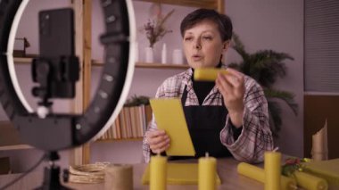 Kadın zanaatkar video yayını yapıyor ya da akıllı telefondan el yapımı mum yapmayı öğreniyor. Kadın cep telefonuyla video bloğu çekiyor, mum yapıyor. Başlangıç, sme ve günlük tutma kavramı