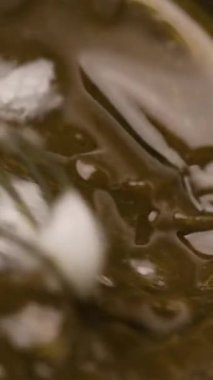 Eritilmiş sıvı karamelli sosla çırpılmış çeliği karıştırıyorum. Yakın plan. Dikey video