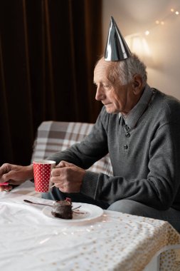 Evde oturarak Yalnız Doğum Günü 'nü kutlayan Sıkıcı Yaşlı Adam. Boşluğu kopyala