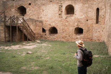 Kıdemli turist tuğla duvarların kemerlerinde sonbahar tatilinde yürüyen antik kalede. Turizm ve seyahat kavramı