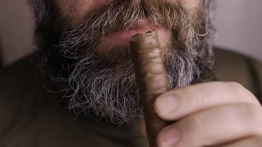 Sakallı adamın ağzı çikolata yiyor, yakın plan.