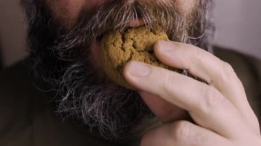 Kahve saatinde yulaf ezmeli kurabiye yiyen sakallı adam, yakın plan..