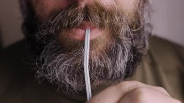 Yemek ve içecek konseptinin cazibesi. Susamış bıyıklı adam samanla soda içip yudumluyor. Yakın plan.