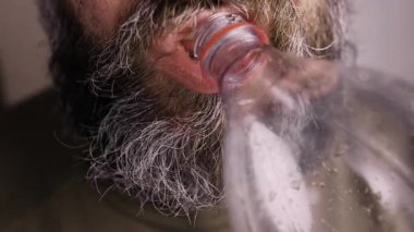 Evdeki şişeden kola içen sakallı adamı yakından çek. içki ve sağlıksız yaşam tarzı konsepti