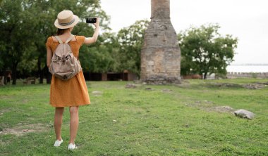 Kadın turist, akıllı telefon, arka plan, fotokopi mekanı kullanarak doğadaki işaretlerin fotoğraflarını çekiyor.