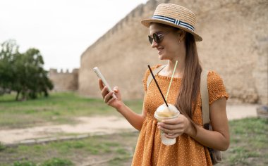 Kadın arka plandaki kale duvarında akıllı telefondan sohbet ediyor. Ortaçağ Kalesi Akkerman. Boşluğu kopyala