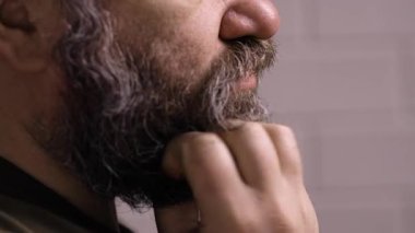 Sakalını kaşıyan sakallı bir adam egzama ya da deri iltihabı yüzünden acı çekiyor. Deri sağlığı konsepti. Kapatın. Yan görünüm