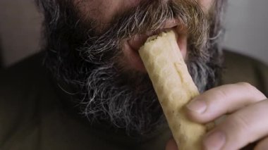 Tatlı konsepti ye. Sakallı bir adam krep yiyor ve yoğun süt dolguluyor. Yakın plan.