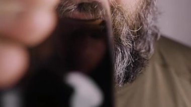 Sakallı adamın bardaktan kola içtiği yakın plan. Bardakta iç.