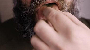 sağlıklı yaşam tarzı konsepti. Yakın plan sakallı adam, diline hap, içme suyuna da ilaç ve vitamin alıyor. Kırpılmış görünüm